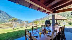 An outdoor dining area with a table set for four, overlooking a mountainous landscape.