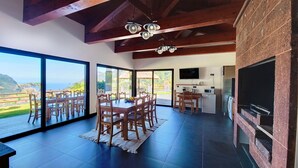 A spacious dining area with a large table and chairs, a kitchen with appliances, and a view of the outdoors.