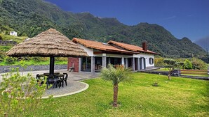 A house with a thatched roof and a patio with outdoor furniture.