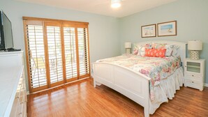 A bedroom with a bed, a ceiling fan, a nightstand, a lamp, a dresser, and a window with blinds.