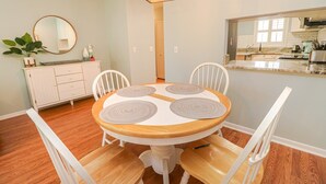 A dining area with a round table, white chairs, and a white cabinet with drawers.