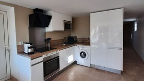 Una cocina compacta con estufa, microondas y lavadora.