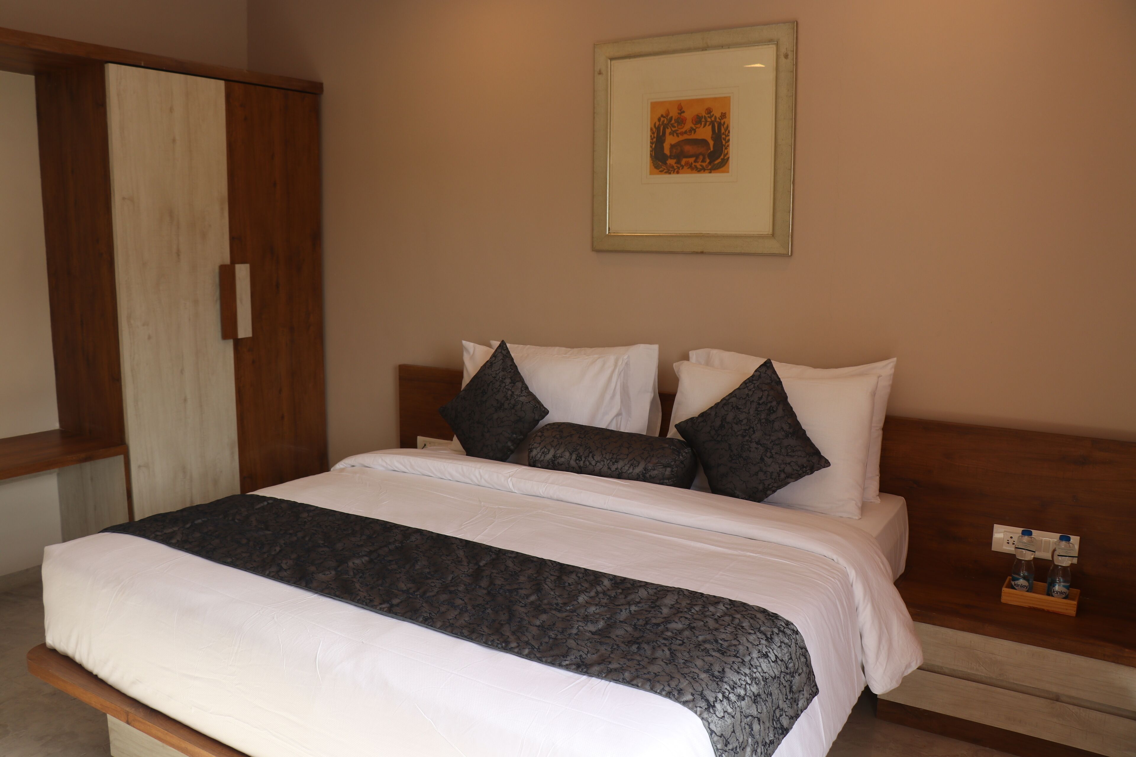 A neatly made bed with white and gray bedding, a wooden headboard, and a framed picture on the wall.