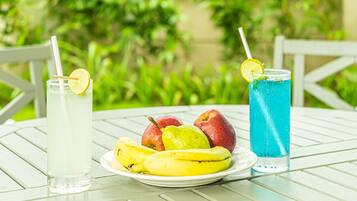 Una mesa con un plato de fruta, un vaso de líquido transparente y un vaso de líquido azul.