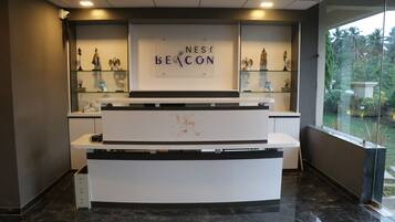 A reception desk with a sign reading "NEST BEACON" and glass display cases with figurines.