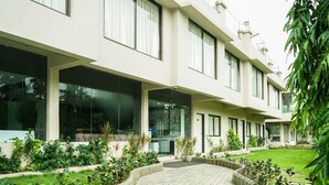 Un edificio moderno con grandes ventanales, un patio empedrado y jardines bien cuidados.