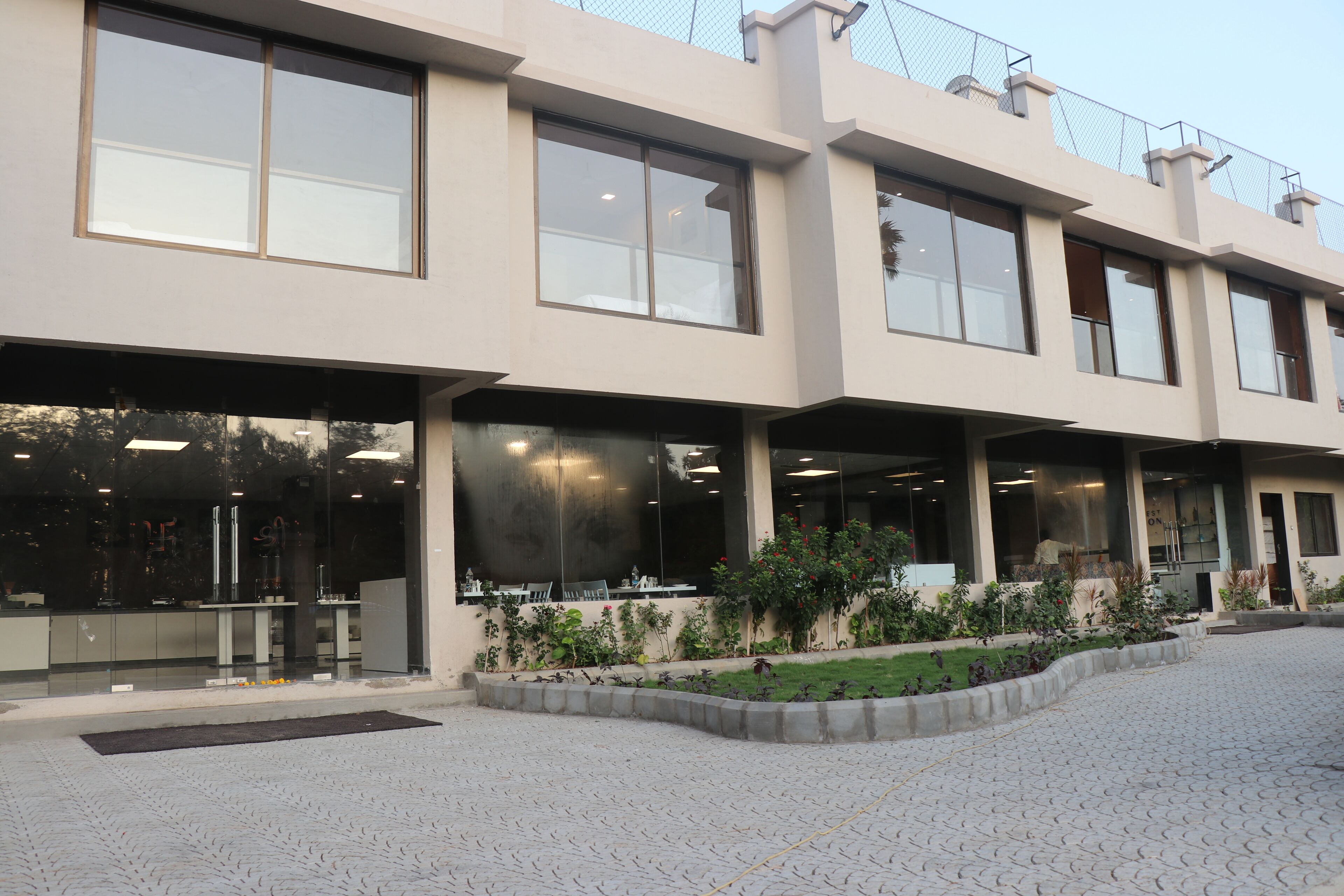 A modern building with large windows, a paved courtyard, and outdoor seating.
