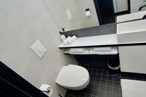 Uma casa de banho moderna com sanita, lavatório e porta-toalhas.