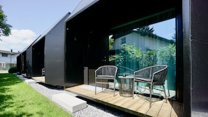 A modern building with a covered outdoor area featuring two wicker chairs and a small table. - Chalet Park by Maier Mäder (Mäder)