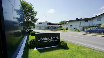 A sign for Chalet Park Maier with a well-maintained lawn and a road in the background.