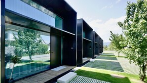 A modern building with large windows, a wooden deck, and a well-maintained lawn. - Chalet Park by Maier Mäder (Mäder)