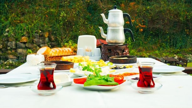Une table mise pour un repas, avec différents plats, une théière et des verres à thé.