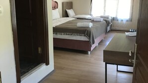 Une chambre d’hôtel avec un grand lit, un plus petit lit, un bureau et une fenêtre avec des rideaux.