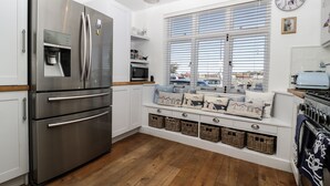 Eine moderne Küche mit Edelstahlgeräten, einer integrierten Sitzecke mit Körben und Blick durch große Fenster.