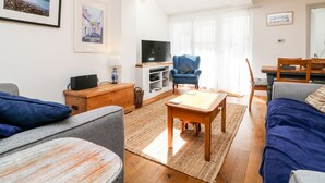 Ein Wohnzimmer mit einer Couch, einem Couchtisch, einem Fernseher und einem Sessel.
