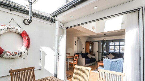 Schiffsinnenraum mit Essbereich, Wohnbereich mit Sofa und Schrank, sowie einem Rettungsring an der Wand.