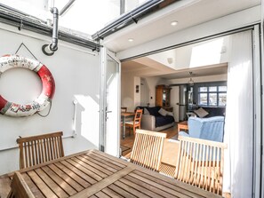 A boat interior with a dining area, a living space with a sofa and a cabinet, and a lifebuoy on the wall. - Ferriwais (Bideford)