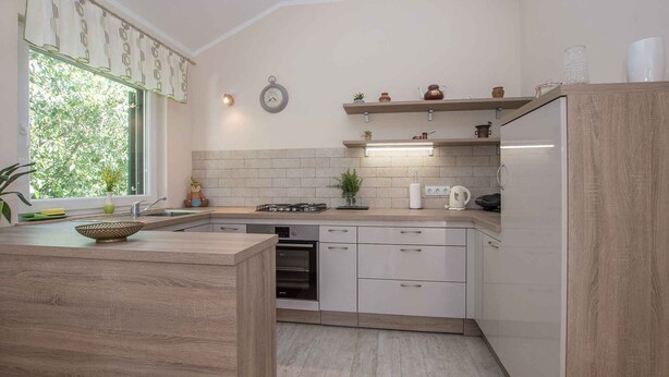Une cuisine moderne équipée d’un four encastré, d’un évier et d’une cuisinière. On y trouve également des placards et un plan de travail.