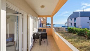 A balcony with a table and chairs, a glass door, and a view of the sea and buildings. - Holiday apartment with air conditioning near the sea (Lovrečica)