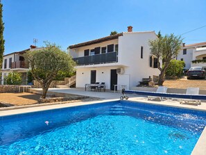 Una casa moderna de dos pisos con una piscina al frente.