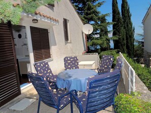 An outdoor patio with a round table and chairs, a satellite dish, and a view of the sea.