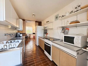 A modern kitchen with white cabinets, a stainless steel countertop, a microwave, and a stove. - Holiday apartment 10 m from the beach (Malinska)
