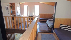A multi-level room with a wooden staircase, a bed with striped pillows, and a view of a kitchen area. - Holiday apartment 10 m from the beach (Malinska)