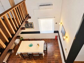 A dining area with a wooden staircase, a table with chairs, a window, and a wall-mounted air conditioner. - Holiday apartment 10 m from the beach (Malinska)