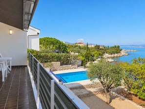 A balcony with a pool overlooking a coastal area.