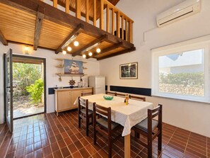 A kitchen with a dining table, chairs, a window, and a view of greenery outside.