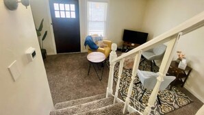 A staircase leading to a living room with a television, a small table, and a chair. - The Tiny Piney Loft - Live. Work. Play. Downtown Green Bay! (Green Bay)