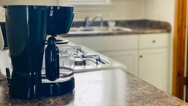 A coffee maker on a kitchen counter with a window in the background. - The Tiny Piney Loft - Live. Work. Play. Downtown Green Bay! (Green Bay)