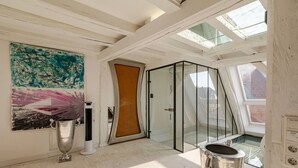 A modern room with a glass door, a large abstract painting, and a metal container.