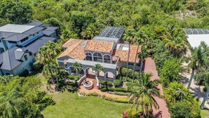 An aerial view of a large, multi-story building with a tiled roof, surrounded by lush greenery and palm trees. - STARFISH OASIS - NEW TO RENTALS! (Sanibel)