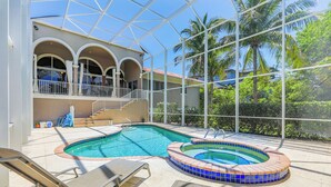 A swimming pool with a hot tub, lounge chairs, and a covered area with a view of palm trees. - STARFISH OASIS - NEW TO RENTALS! (Sanibel)