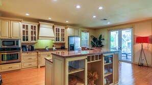 A kitchen with wooden cabinets, a central island, a refrigerator, and a microwave.