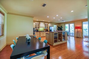 A spacious kitchen with wooden cabinets, a dining table with chairs, and a red floor lamp.