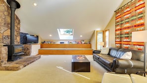 A living room with a stone fireplace, a sofa, a coffee table, and a television.