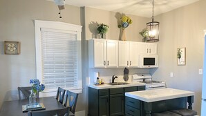 A modern kitchen with white cabinets, a black countertop, and a dining area with a table and chairs. - Beautiful Benton Beauty (Saint Charles)