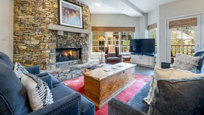 A cozy living room with a stone fireplace, comfortable seating, and a flat-screen TV. - Ultimate Location by InvitedHome | Hike, Bike, Shops, Restaurants, Gondola (Mountain Village)