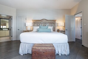 Une chambre à coucher avec un grand lit, une tête de lit en bois, deux tables de chevet avec des lampes et un banc en bois.