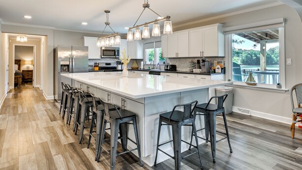 A modern kitchen with a large island, bar stools, and pendant lighting.