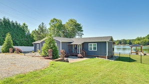 A two-story house with a covered porch, a fenced yard, and a lake view.