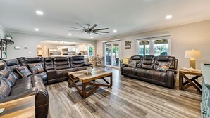 A spacious living room with leather sofas, a wooden coffee table, and a ceiling fan.