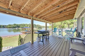 Una terrazza coperta con barbecue, sedie da esterno e vista su un lago.
