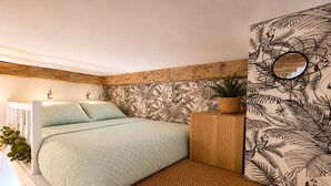 A bedroom with a bed, a nightstand, a potted plant, and a wall with a leaf pattern.