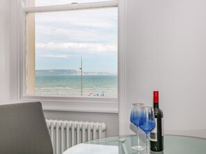 Ein Zimmer mit Meerblick, ein Tisch mit Flasche und Gläsern sowie ein Stuhl.