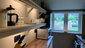 Una cocina moderna con cafetera, hervidor y microondas sobre la encimera. Hay una ventana con vistas al exterior.