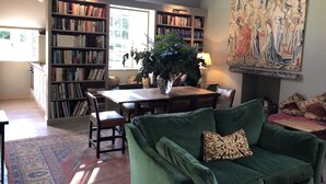 Una sala de estar con un sofá verde, una mesa de comedor y una estantería llena de libros.