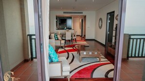 Un grand espace de vie comprenant une table à manger et des chaises, un canapé et un tapis aux motifs rouges et noirs.